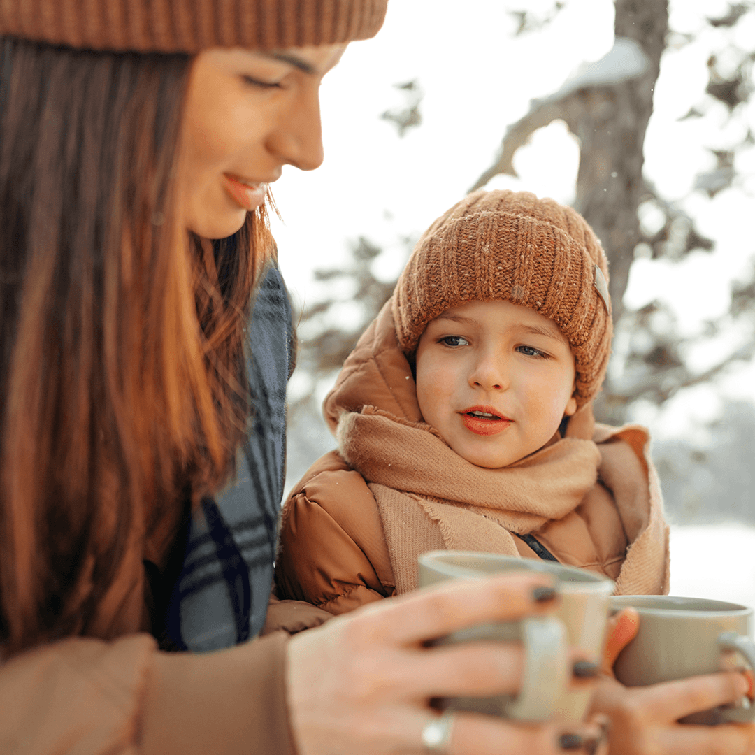 Mutter und Kind essen draußen im winterlichen Wetter.