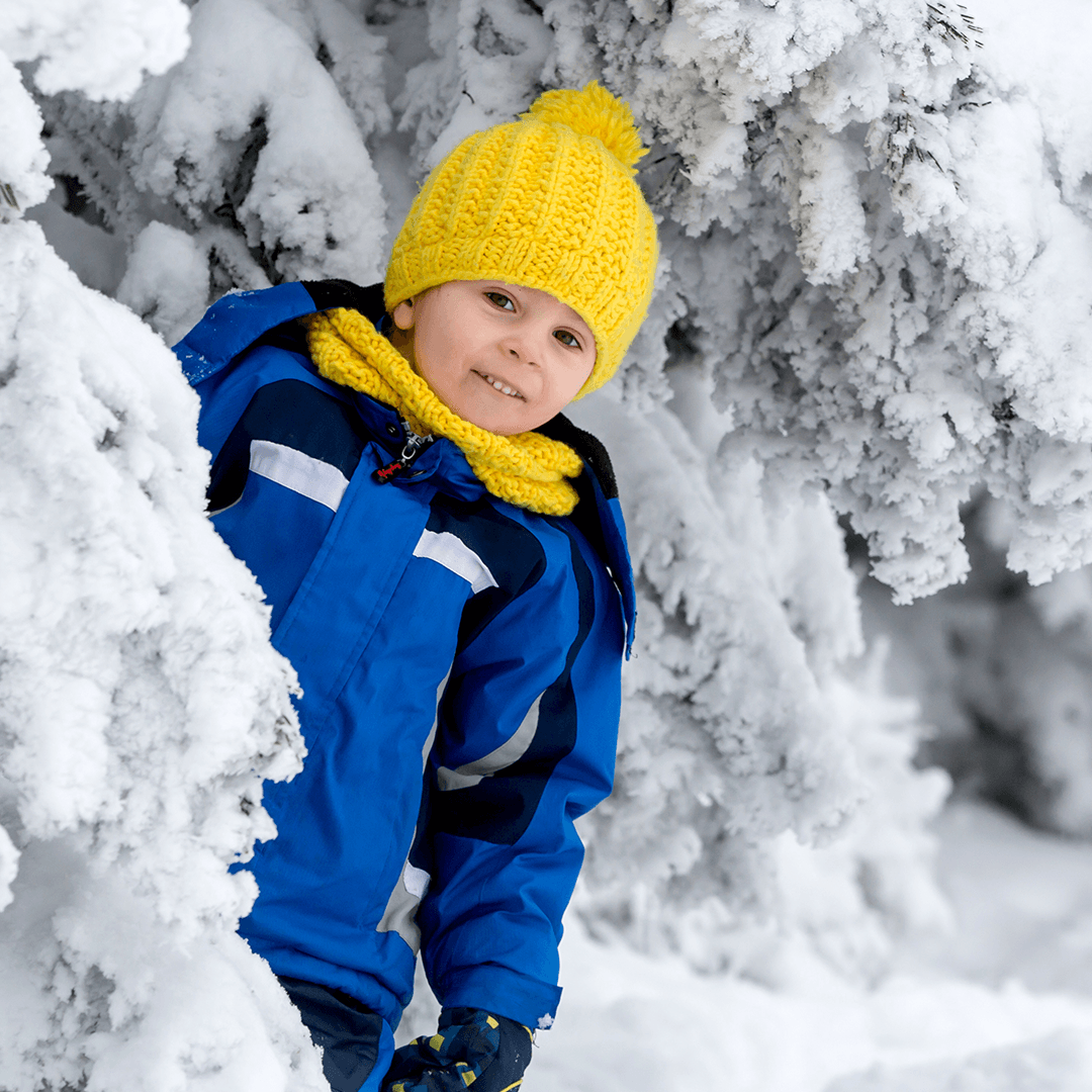 Junge spielt draußen im Schnee an einem Winterferientag
